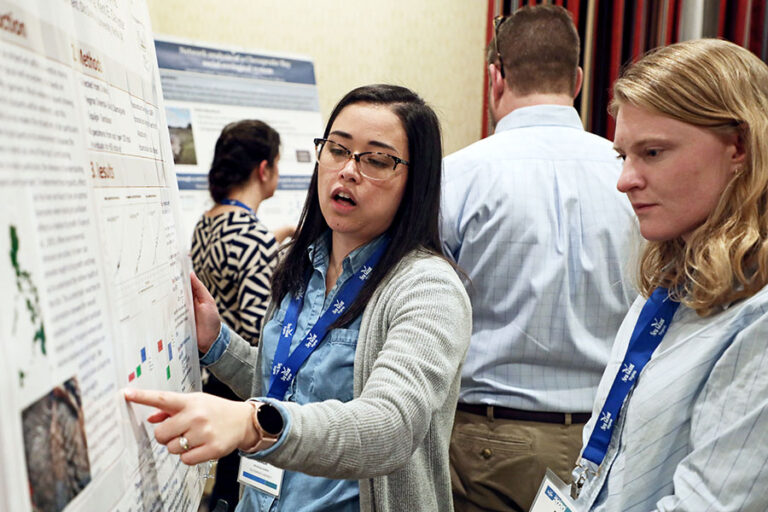 Image of two people examining a research poster.